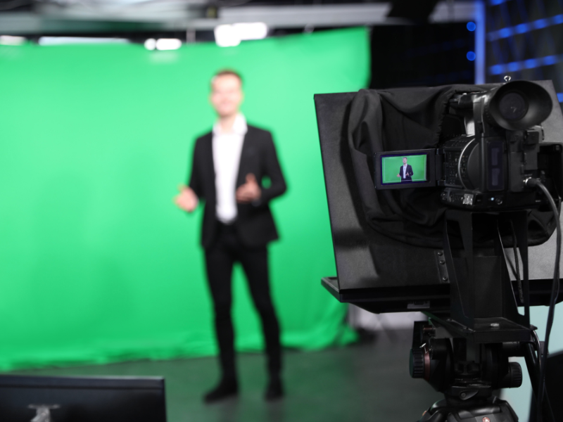 Camera preview screen with subject in the background, a man in front of a green screen